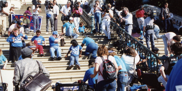 People with disabilities crawl up the steps of the Capitol Building.